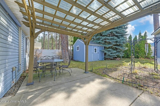 view of patio / terrace with outdoor dining space, an outbuilding, fence, a shed, and a pergola