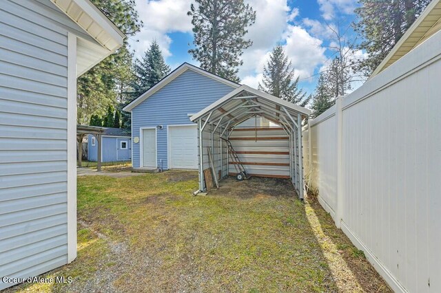 view of yard with a detached garage, an outdoor structure, and fence