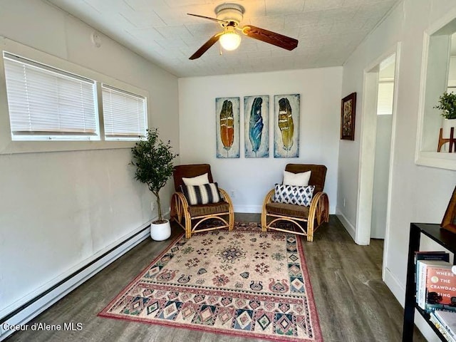 living area featuring a baseboard radiator, baseboards, wood finished floors, and a ceiling fan