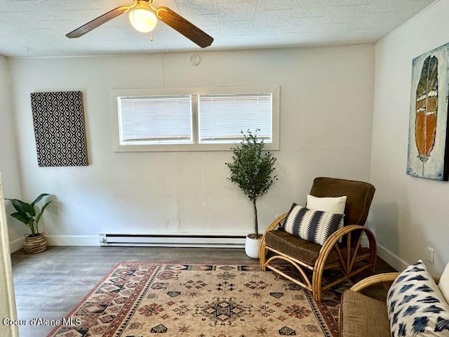 sitting room with a baseboard heating unit, wood finished floors, baseboards, and ceiling fan