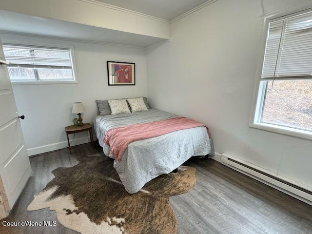 bedroom with crown molding, a baseboard heating unit, baseboards, and wood finished floors