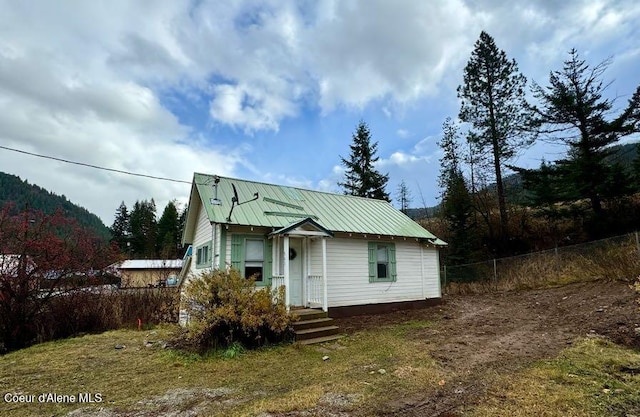 view of front of house featuring metal roof and fence