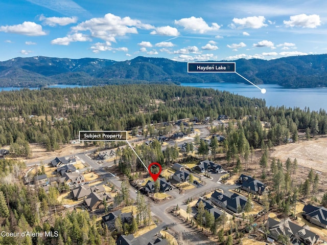 birds eye view of property featuring a forest view and a water and mountain view