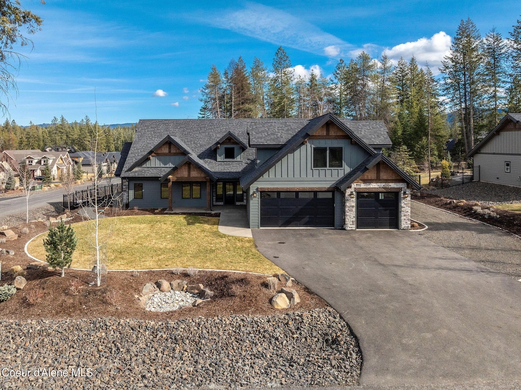 view of front of property with board and batten siding, a front lawn, roof with shingles, driveway, and an attached garage