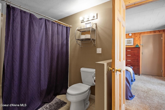 bathroom featuring a shower with curtain, wooden walls, toilet, and a textured wall