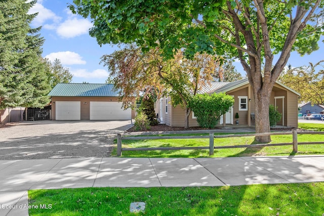 view of front facade with a fenced front yard, driveway, metal roof, and a front lawn