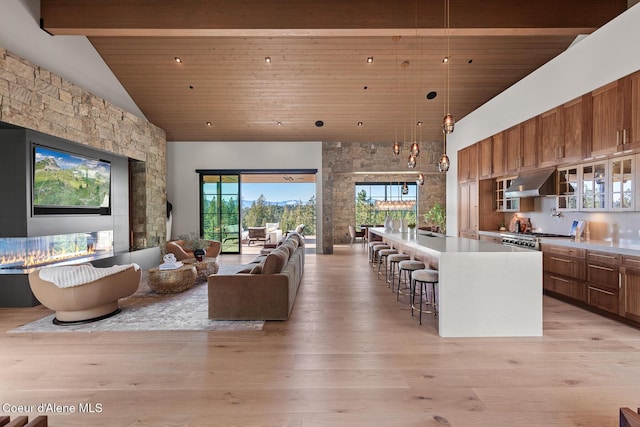 living area featuring beamed ceiling, high vaulted ceiling, wooden ceiling, and light wood finished floors