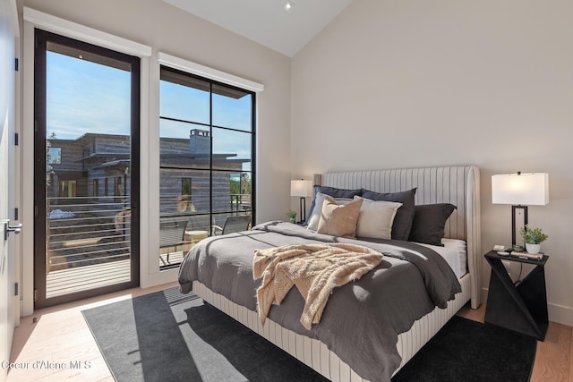 bedroom featuring access to exterior, wood finished floors, and lofted ceiling