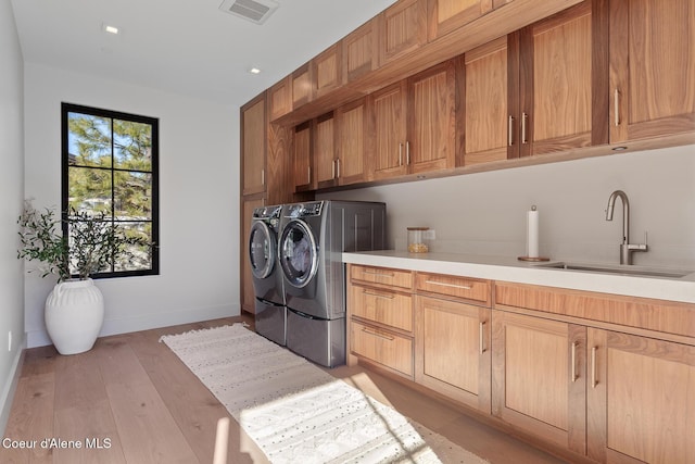 laundry area featuring visible vents, a sink, baseboards, cabinet space, and separate washer and dryer