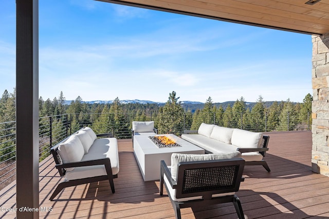 deck with an outdoor living space with a fire pit, a mountain view, and a wooded view