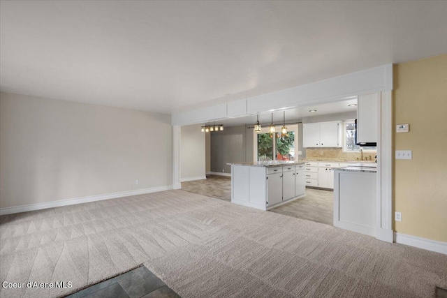 kitchen with backsplash, a center island, white cabinetry, light countertops, and light colored carpet