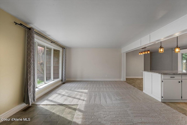 unfurnished living room featuring visible vents, light colored carpet, and baseboards