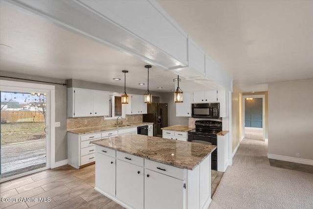 kitchen featuring a sink, black appliances, white cabinetry, tasteful backsplash, and a center island