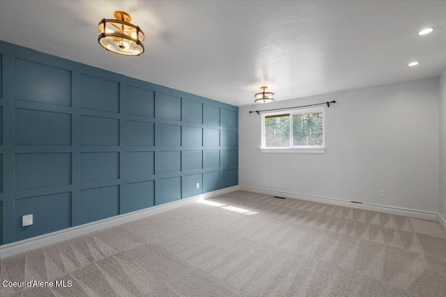 empty room with baseboards, carpet flooring, recessed lighting, a notable chandelier, and a decorative wall