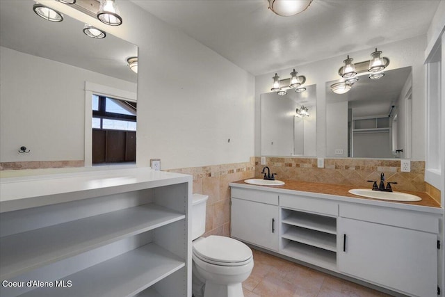 full bath with a sink, tile walls, double vanity, and tile patterned flooring