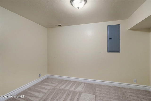 carpeted empty room with electric panel, visible vents, baseboards, and a textured ceiling