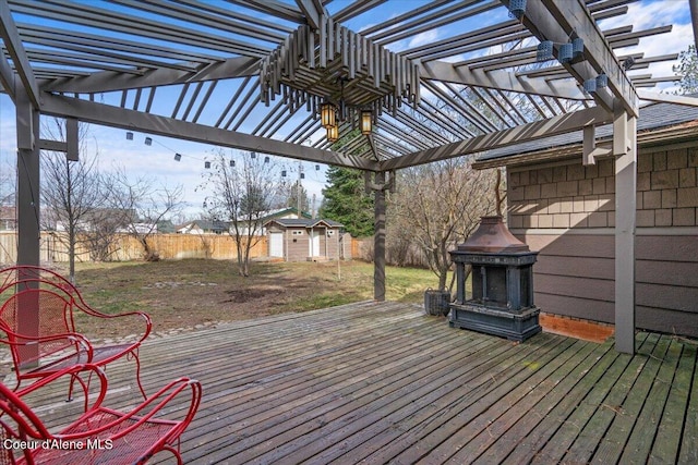 wooden terrace with a storage shed, a yard, a fenced backyard, an outbuilding, and a pergola