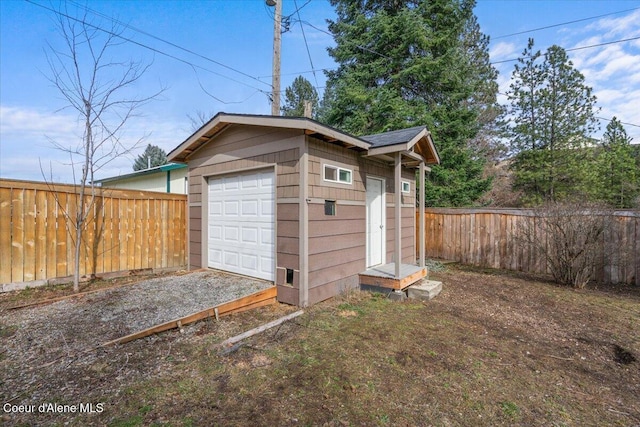 detached garage featuring driveway and fence