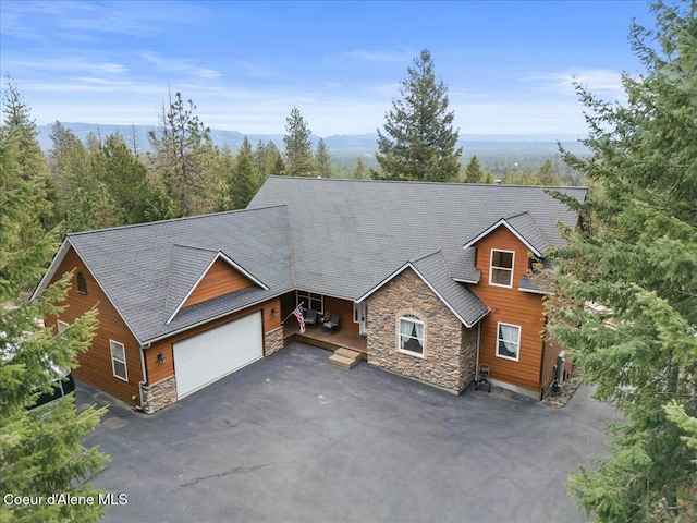 view of front of home with aphalt driveway, stone siding, and an attached garage