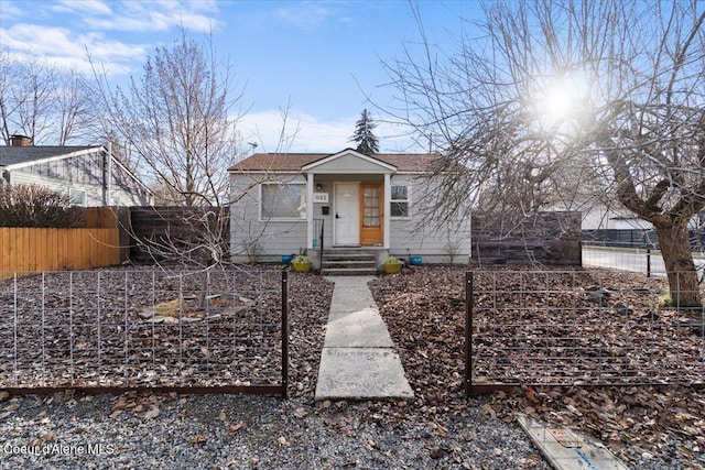 bungalow-style house with fence and a shingled roof