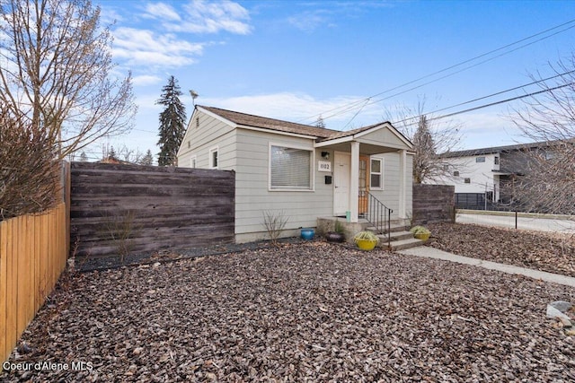 bungalow-style home with fence private yard and roof with shingles