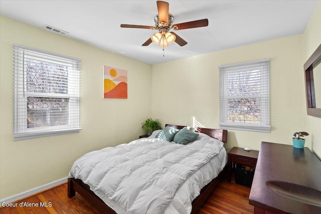 bedroom with multiple windows, wood finished floors, visible vents, and baseboards