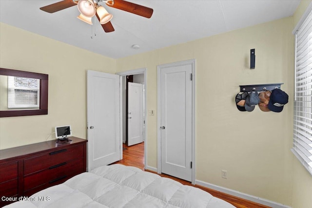 bedroom with baseboards, wood finished floors, and a ceiling fan