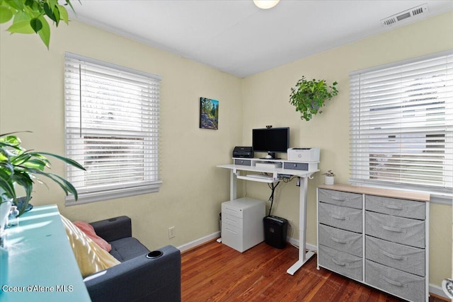 office space with dark wood-type flooring, plenty of natural light, baseboards, and visible vents