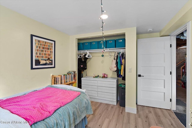 bedroom with wood finished floors, a closet, and baseboards