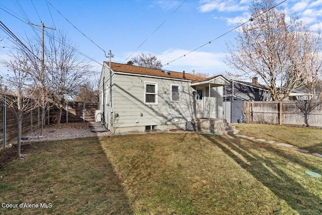 rear view of property featuring a lawn and a fenced backyard