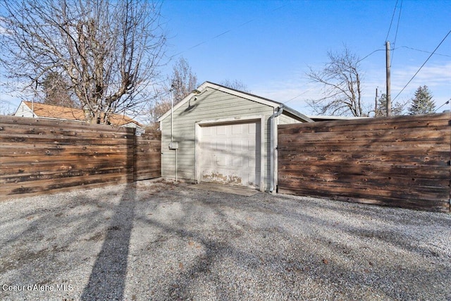 garage featuring gravel driveway and fence