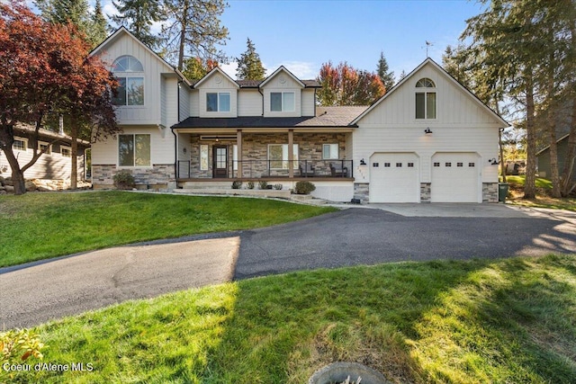 view of front of house with aphalt driveway, a porch, a front yard, stone siding, and an attached garage