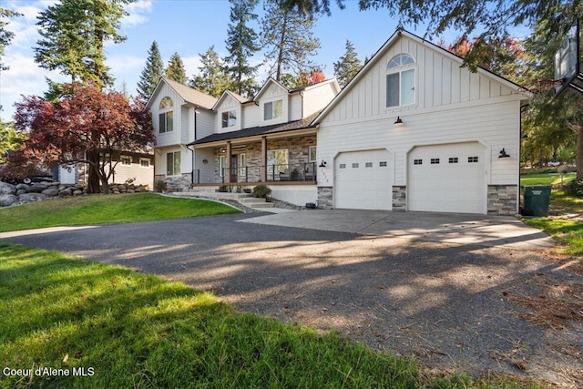 view of front of property with driveway, stone siding, board and batten siding, covered porch, and an attached garage