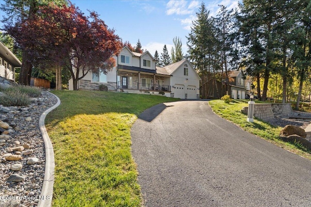 view of front facade featuring driveway, covered porch, a front lawn, stone siding, and a garage