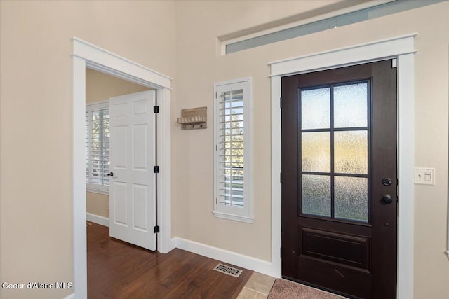 foyer featuring dark wood finished floors, plenty of natural light, baseboards, and visible vents