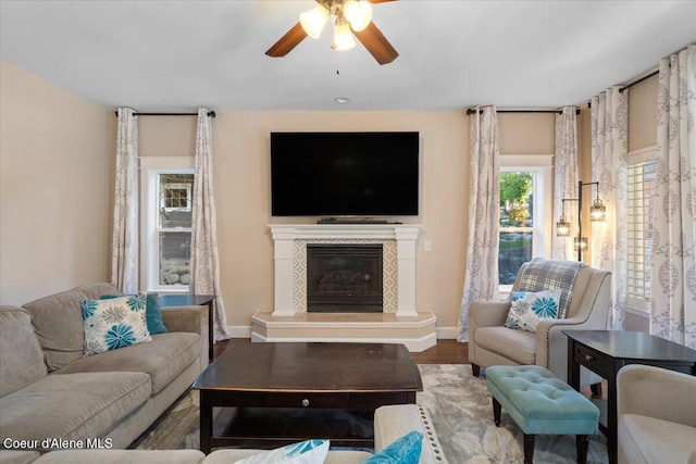 living area featuring ceiling fan, wood finished floors, baseboards, and a premium fireplace