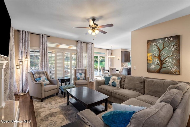 living room with a premium fireplace, ceiling fan with notable chandelier, and wood finished floors