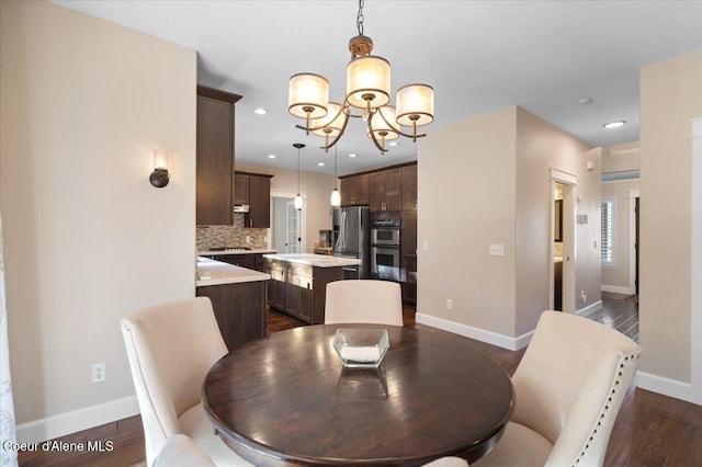 dining space featuring dark wood-type flooring, baseboards, and a chandelier