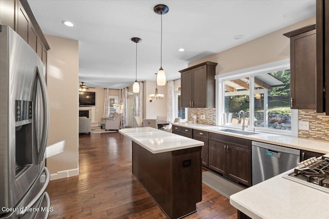 kitchen with dark brown cabinetry, open floor plan, appliances with stainless steel finishes, and a sink