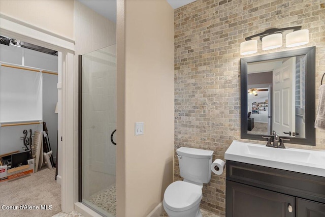 bathroom featuring vanity, toilet, a stall shower, and brick wall