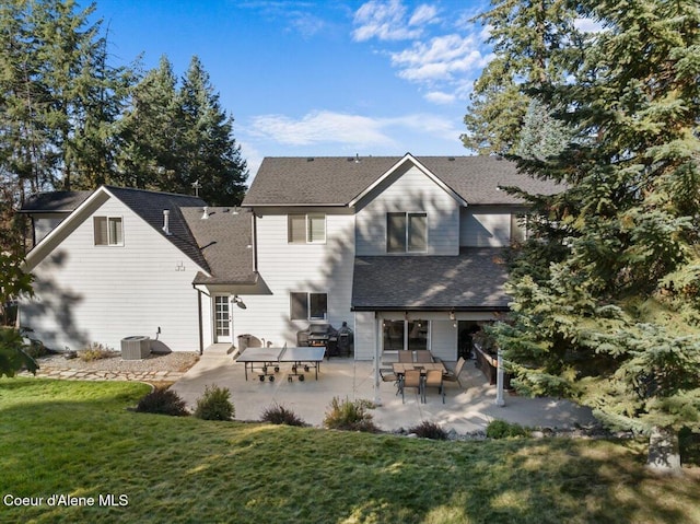 back of property with entry steps, roof with shingles, central AC unit, a lawn, and a patio area