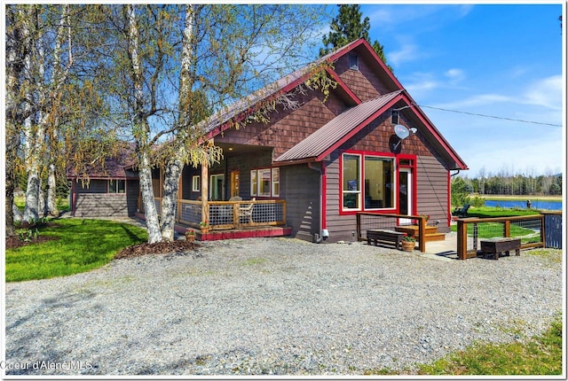 view of front facade with a standing seam roof, covered porch, a water view, and metal roof