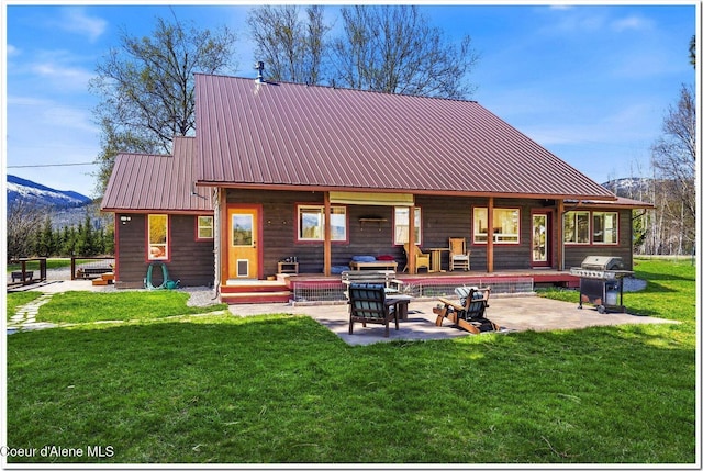 rear view of property featuring a lawn, metal roof, a mountain view, and a patio area