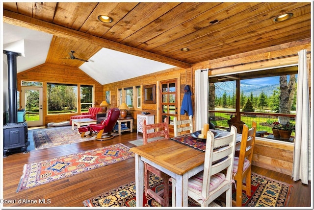 dining room featuring a wood stove, wood ceiling, vaulted ceiling, and hardwood / wood-style floors