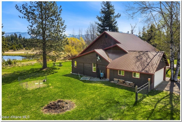 view of home's exterior with a water view, a yard, and a detached garage