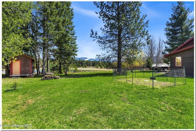view of yard featuring a storage unit, a mountain view, fence, and an outbuilding
