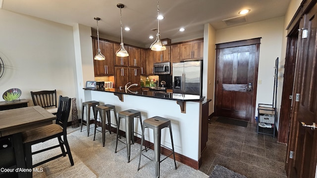 kitchen featuring dark countertops, a breakfast bar area, recessed lighting, granite finish floor, and stainless steel appliances