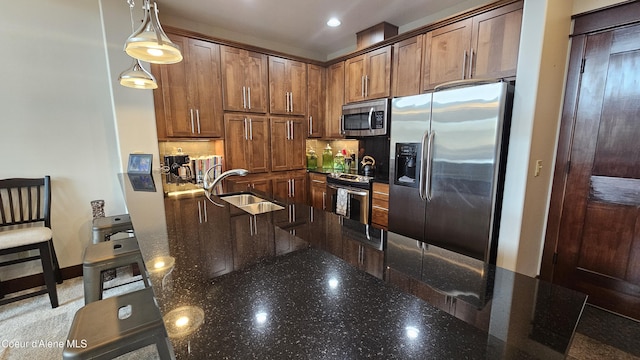 kitchen featuring a sink, dark stone countertops, backsplash, appliances with stainless steel finishes, and hanging light fixtures