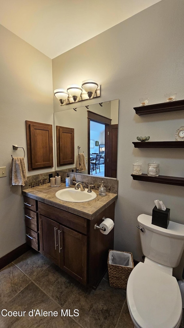 half bathroom with vanity, tile patterned floors, and toilet