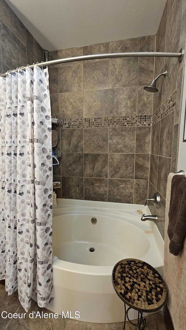 full bath with shower / bath combination with curtain and a textured ceiling